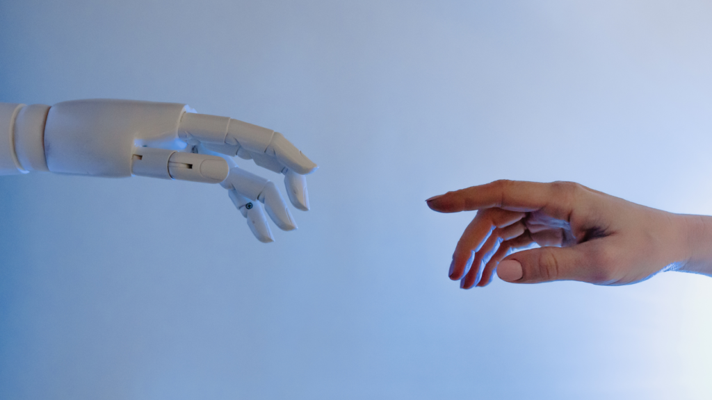 A robot hand and human hand reach out to touch one another.